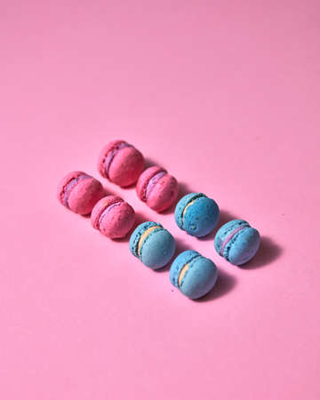 Beautiful variety of macaroons in a row on pink background, top view