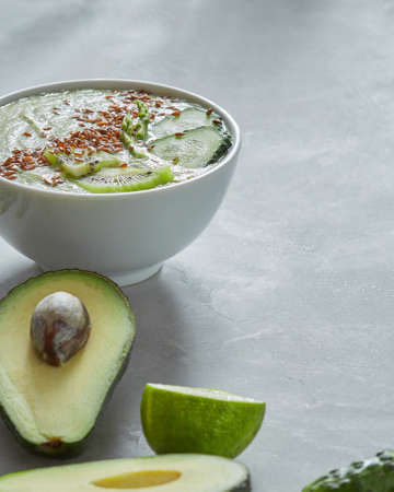 In a white plate smoothies of cucumber and avocado with kiwi and flax seeds on a gray concrete background.の写真素材