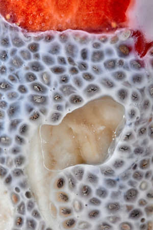 Macro photos of chia seeds in yogurt with pieces of fruit in a clear glass.の写真素材