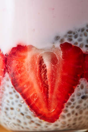Macro photo of a strawberry half with chia seeds and yogurt in a clear glass.の写真素材