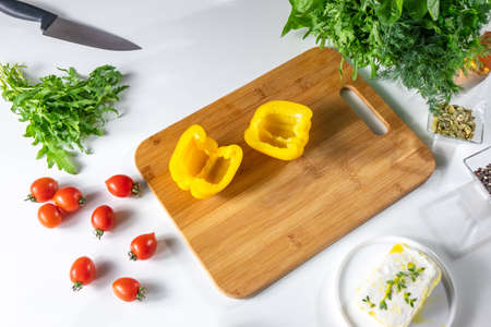 A set of vegetables, tomatoes, peppers, greens and cheese for a healthy salad on a white kitchen...