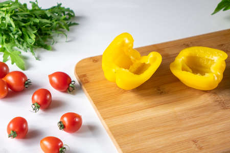 Vegetables for salad.Cherry tomatoes, yellow pepper, arugula, on a white kitchen table.