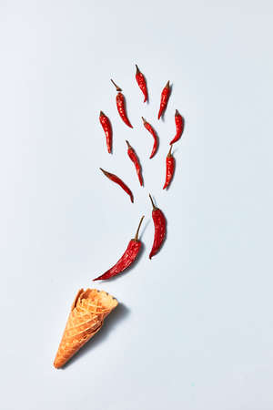 hot chili peppers in wafer cones on gray background, top view