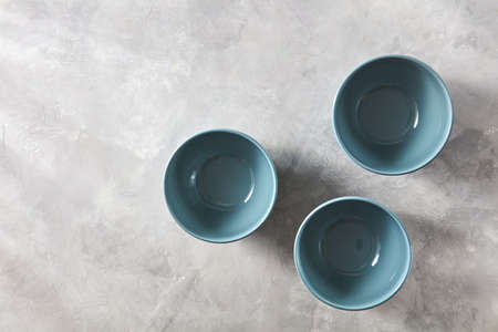 Three blue hand crafted chinese bowls on gray stone background. Flat layの写真素材