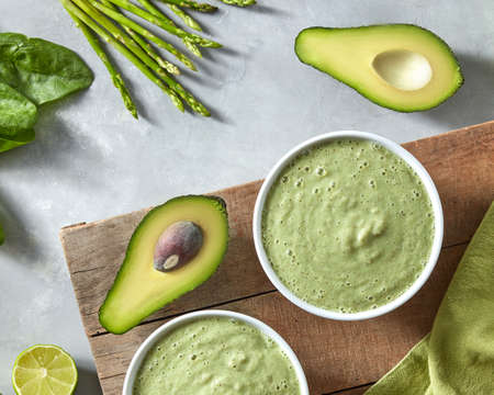 Breakfast of fresh green smoothies in a pial with avocado on a concrete background with a green...