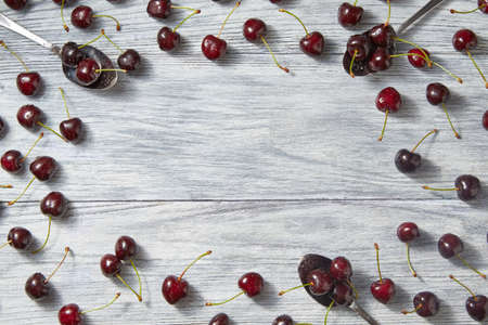 Colorfiul fruits pattern with three spoons with red juicy ripe cherries and berries on a gray wooden...