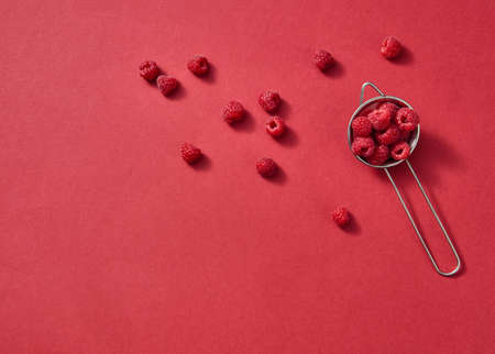 Fruits pattern of fresh summer raspberries on a red background. Top view.の写真素材