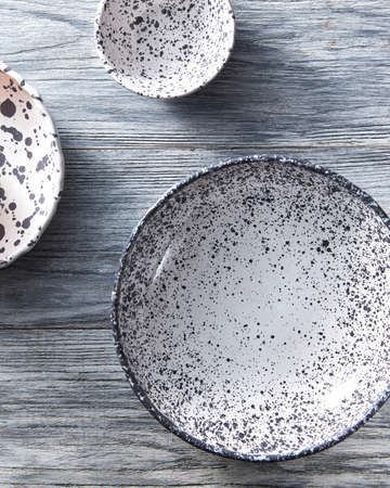 Set of handcrafted porcelain bowls on a gray wooden table. Vintage painted plates dishes. Flat lay.の写真素材