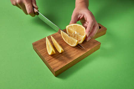 Concept of healthy food. Female hands cut a juicy green ripe lime to slices for making homemade healthy drinks.の写真素材
