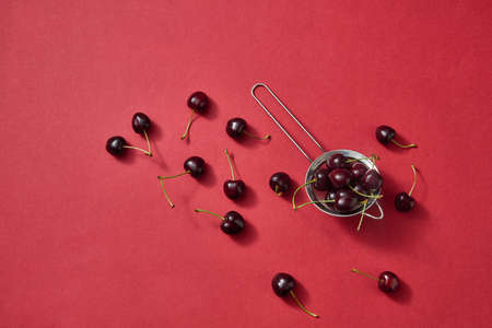 Colorfiul pattern with red juicy cherries on a red paper background. Top viewの写真素材