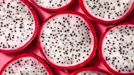 Flat lay view of background from round slices of Dragon fruit or Pitaya on a pink background.の写真素材