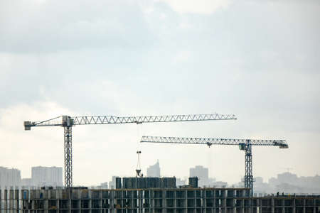 Industrial landscape with silhouettes of cranes on the gray cloudy background.の写真素材