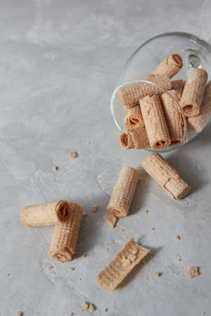 Crispy dessert - waffle rolls lie in a glass on a gray background. Top view