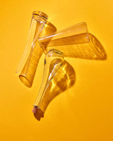 Empty glass bottles lie on a yellow background with shadows and reflection. Top view.の写真素材