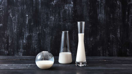 Three glasses with dairy product milk or yogurt standing on a black wooden table on a black. Natural organic dairy product.の写真素材