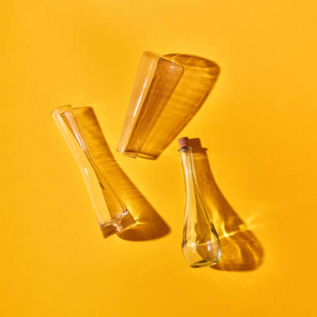 A transparent glass vases empty lie on a yellow paper background with soft shadows. Top view.の写真素材