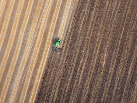 Agricultural field after harvesting and part of the field plowed of tractor under sowing works .