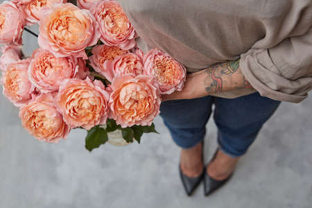Stylish woman holding a bouquet of pink roses on a gray background.Day for Valentines Day. Top view