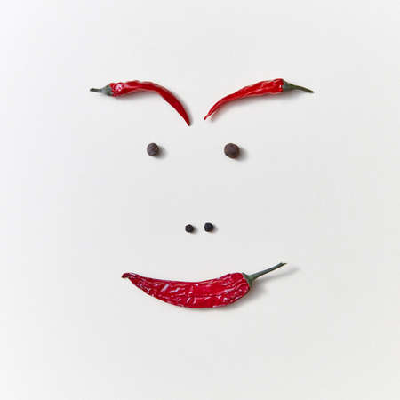 Creative pattern from red ripe chili pepper and pepper seeds in the form of mans face isolated on...