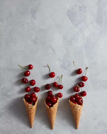 Fresh summer pattern of ripe organic fruits in a sweet cones on a gray marble table.