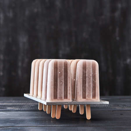 Cold dessert, coffee ice cream on a stick in the molds on a dark wooden table with copy space.の写真素材