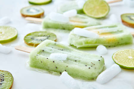 Frozen fruit juice lolly with a piece of peach and pieces of fruit and ice on a gray background....