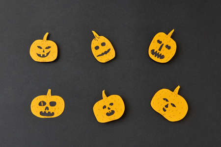 Handcraft decoratide pattern from flying smiling and laughing yellow pumpkins on a black background.
