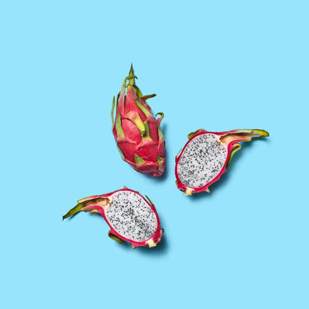 Half and whole fruit of Pitahaya or dragon eye on a blue background with space for text. Top viewの写真素材