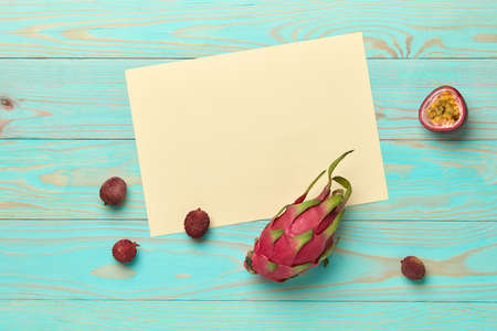 Frame decorated with fruit pitahaya, lychee and passion fruit on a wooden blue background with space...