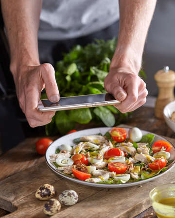 Appetizing healthy salad from organic ingredients in a plate with mens hand making the photo by...