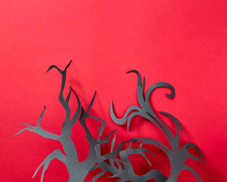 Halloween composition of paper handcraft branches of trees on a red background with space for text. Postcard. Flat layの写真素材