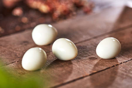 Cooking peeled quail eggs presented on an old wooden table. Ingredient for Healthy Salad.