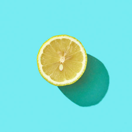 Fresh half organic lemon on blue background with reflection of shadows and space for text. Ingredient for mojito. Top viewの写真素材