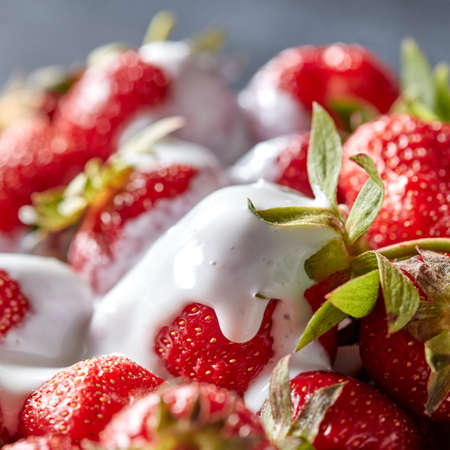 Closeup of juicy organic strawberries with green leaves and fresh cream. Healthy dessertの写真素材