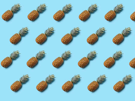 Whole tropical pineapple fruit with green leaves on blue background. Food layout. Flat layの写真素材