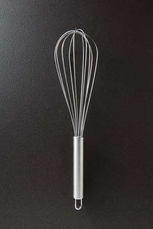 Kitchen metal beater on a black concrete background with copy space. Kitchen appliance for cooking....