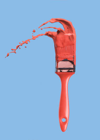 Paintbrush with liquid paint in a color of the year 2019 Living Coral Pantone in color isolated on a...