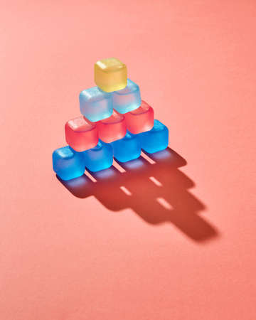 Creative pyramid from colored plastic cubes with liquid, shadows on a background in a color of the...