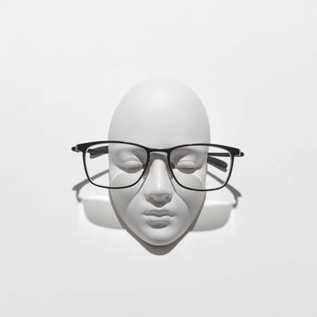 Stylish glasses with black frame for reading daily life on a gypsum face sculpture on a white background, soft shadows, place for text. Flat layの写真素材