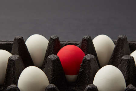 Closeup of black cardboard box with white and red raw eggs on black background with copy space. Easter conceptの写真素材
