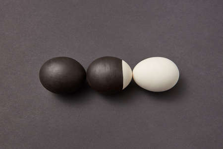 Black and white painted eggs on a black background with copy space. Concept of life change. Flat layの写真素材