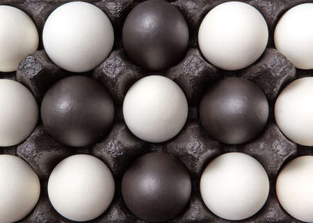Close-up creative pattern of colored black and white eggs in a black cardboard box. Easter composition. Flat layの写真素材