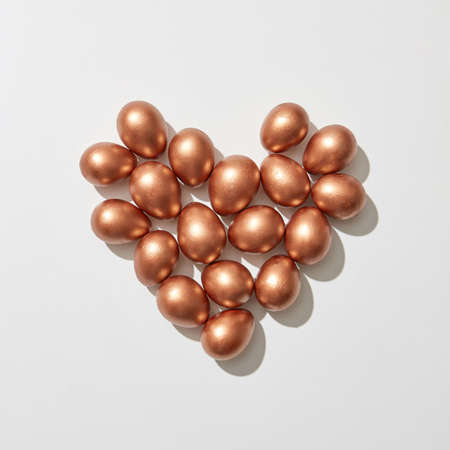 Golden painted eggs in the shape of a heart on a gray background with copy space. St. Valentines Day. Flat layの写真素材