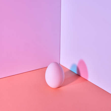 Easter color egg on a multi-colored lilac coral-purple background with a reflection of blue-pink...