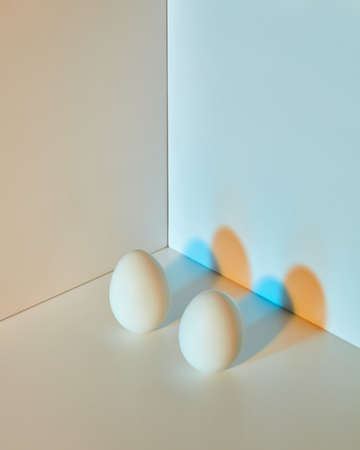 The composition of eggs on a gray-blue double background with copy space and multicolored shadows. Easter concept.の写真素材
