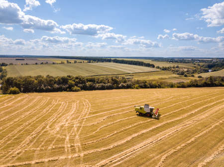 Countryside landscape aerial view from drone to agricultural field with combine on a blue sky background.の写真素材