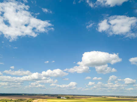 Cloudy aerial landscape with white clouds and fields on a blue sky background. Aerial view from drone.の写真素材