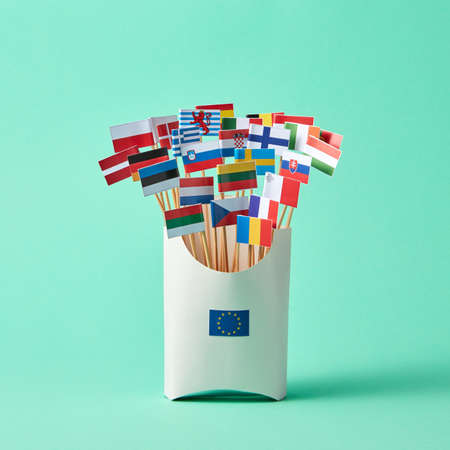 Set of different paper flags in cardboard box decorated with EU sign on green background with copy space. Economic, Political Union of European Statesの写真素材