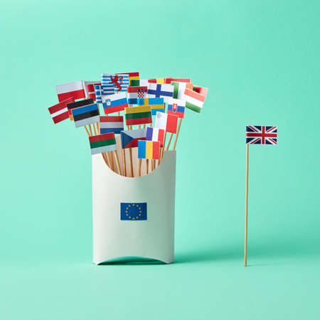 Different paper flags in a cardboard box with an EU sign and flag of Britain aside on green background with copy space. The exit of Britain from the EUの写真素材