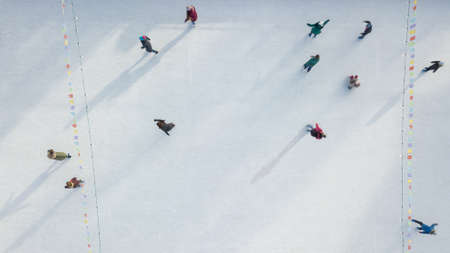 Outdoor ice skating rink with people riding on a winter day. Aerial view from the drone.の写真素材